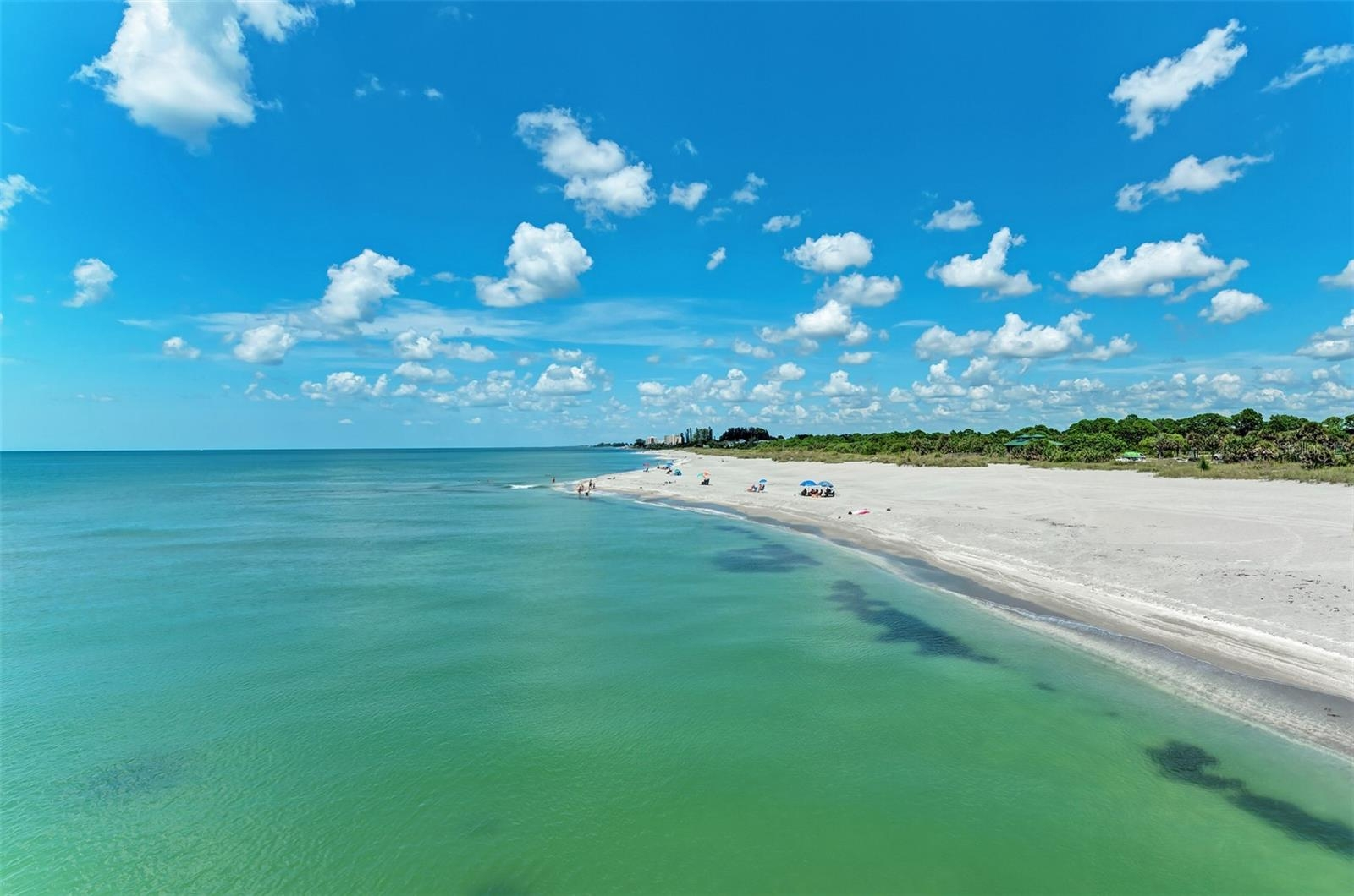 Turquoise Gulf water meeting a wide white-sand beach under a bright blue sky near Venice, Florida